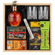 Blanton's Gold Edition Single Barrel Bourbon 700ml gift crate with gold horse stopper, crystal-cut old fashioned glasses, Royal Reserve whiskey stones set with tray, Montecristo Platinum cigar tube, Black Rifle Coffee Tactisquatch blend, Chocolove Almonds & Sea Salt dark chocolate bar, and Wonderful Pistachios in black crinkle paper on white background