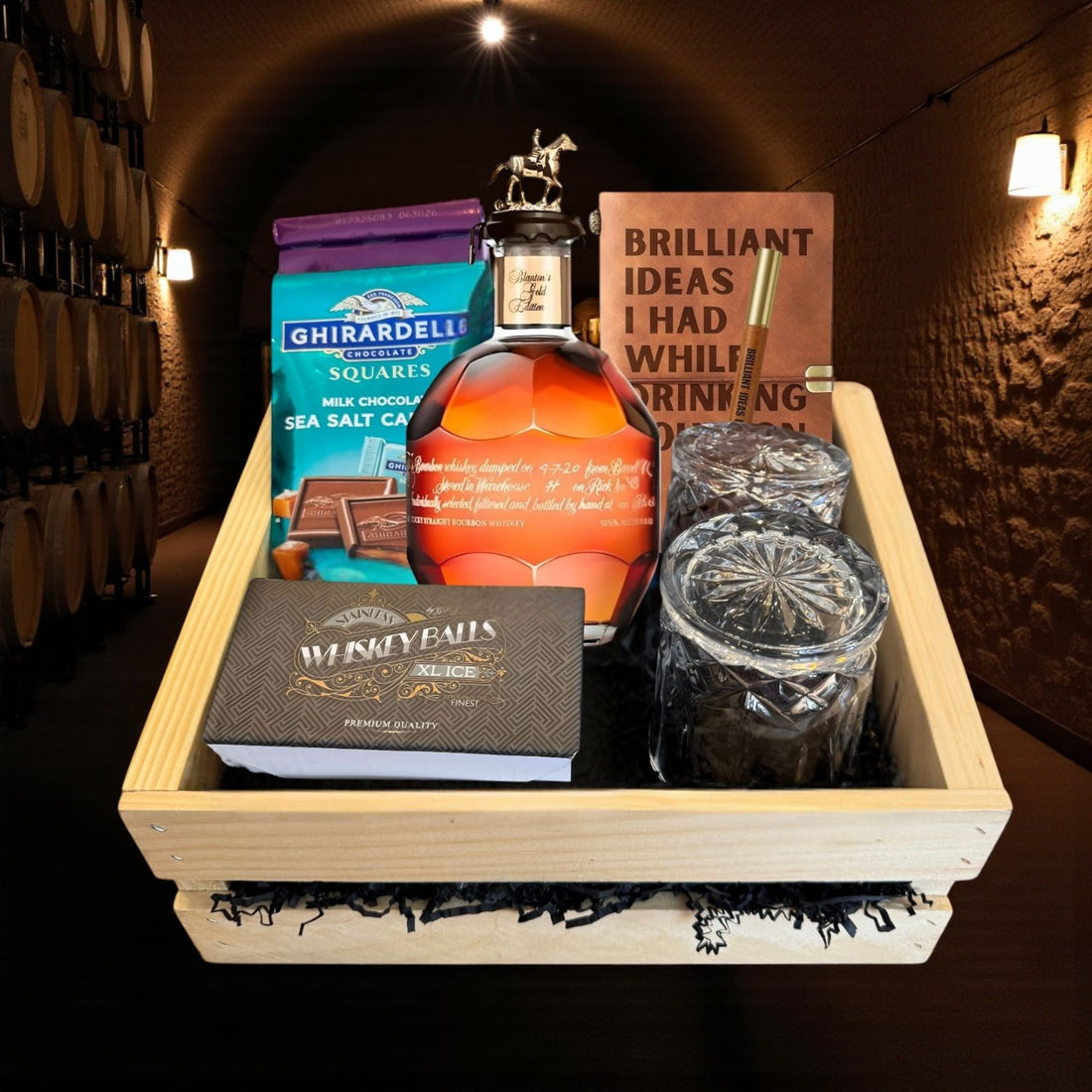 Blanton’s Gold Edition Single Barrel Bourbon Gift Crate with bourbon, glasses, chocolate, and journal displayed in a wooden crate inside a barrel room – premium collector’s gift from Total Bourbon