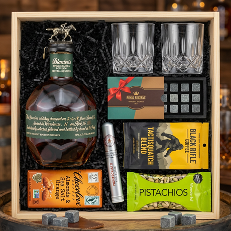 Blanton's Special Reserve Green Label Single Barrel Bourbon 700ml gift crate with bronze horse stopper and green label, crystal-cut old fashioned glasses, Royal Reserve whiskey stones set, Montecristo Platinum cigar, Black Rifle Coffee, Chocolove chocolate, and Wonderful Pistachios on rustic aged oak surface with warm amber bourbon bar lighting and moody bokeh