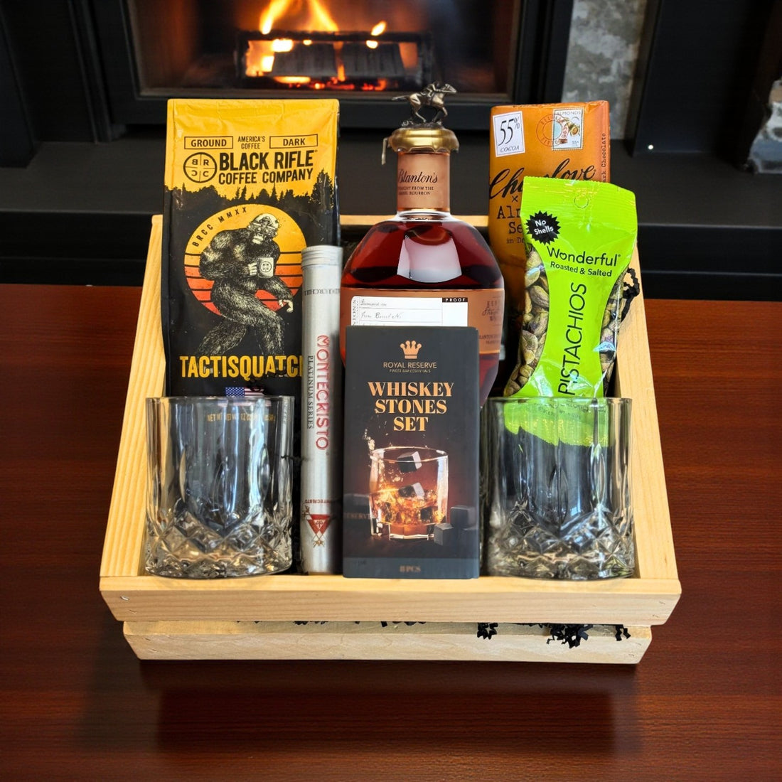 Blanton’s Straight From the Barrel Bourbon Gift Crate with coffee, chocolate, pistachios, cigar, whiskey stones, and glasses in front of a fireplace – lifestyle shot from Total Bourbon