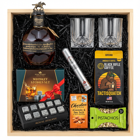 Blanton's Takara Black Edition Single Barrel Bourbon 750ml gift crate with bronze horse stopper and black label with Japanese text, crystal-cut old fashioned glasses, Royal Reserve whiskey stones set with teal/gold box, red ribbon and black wooden tray with 10 grey speckled granite stones, Montecristo Platinum cigar tube, Black Rifle Coffee Tactisquatch blend, Chocolove Almonds & Sea Salt dark chocolate bar, and Wonderful Pistachios in black crinkle paper on white background
