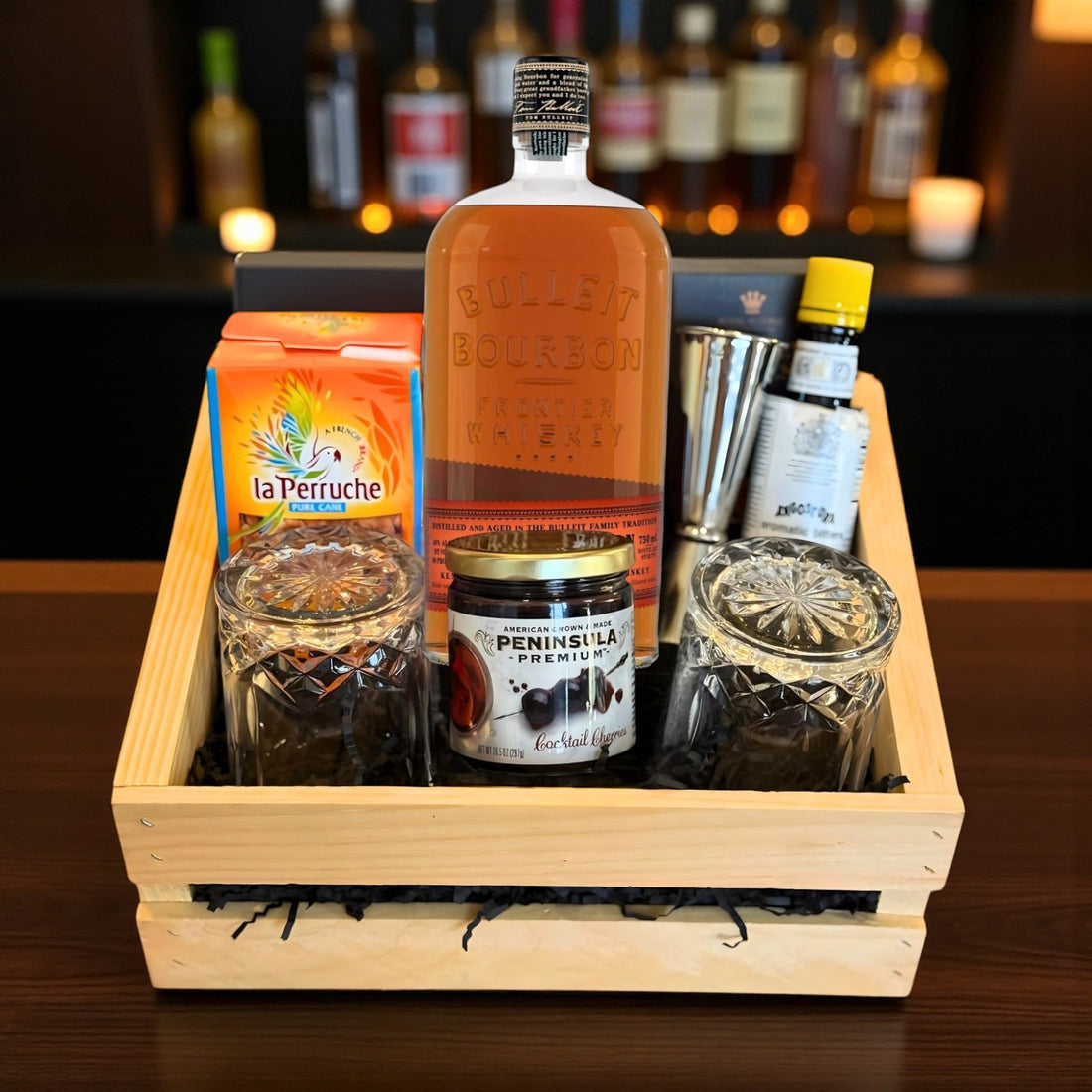 Bulleit Bourbon Old Fashioned Gift Crate with whiskey, bar tools, cherries, bitters, and glasses displayed on wooden bar – lifestyle photo from Total Bourbon