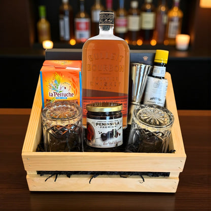 Bulleit Bourbon Old Fashioned Gift Crate with whiskey, bar tools, cherries, bitters, and glasses displayed on wooden bar – lifestyle photo from Total Bourbon