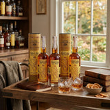 Bottles of Colonel E.H. Taylor Whiskey on a wooden tray with glasses and snacks, in a cozy room.