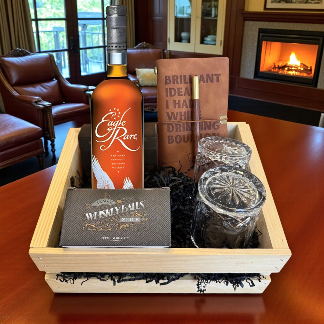 Eagle Rare 10 Year Bourbon Gift Crate on wood table near fireplace with old-fashioned crystal-cut glasses, whiskey balls, and leather journal – lifestyle shot from Total Bourbon