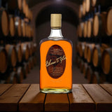 Elmer T. Lee Single Barrel Sour Mash Bourbon bottle displayed on a wooden barrel table in a dimly lit bourbon rackhouse – premium Kentucky bourbon from Total Bourbon