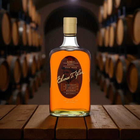 Elmer T. Lee Single Barrel Sour Mash Bourbon bottle displayed on a wooden barrel table in a dimly lit bourbon rackhouse – premium Kentucky bourbon from Total Bourbon