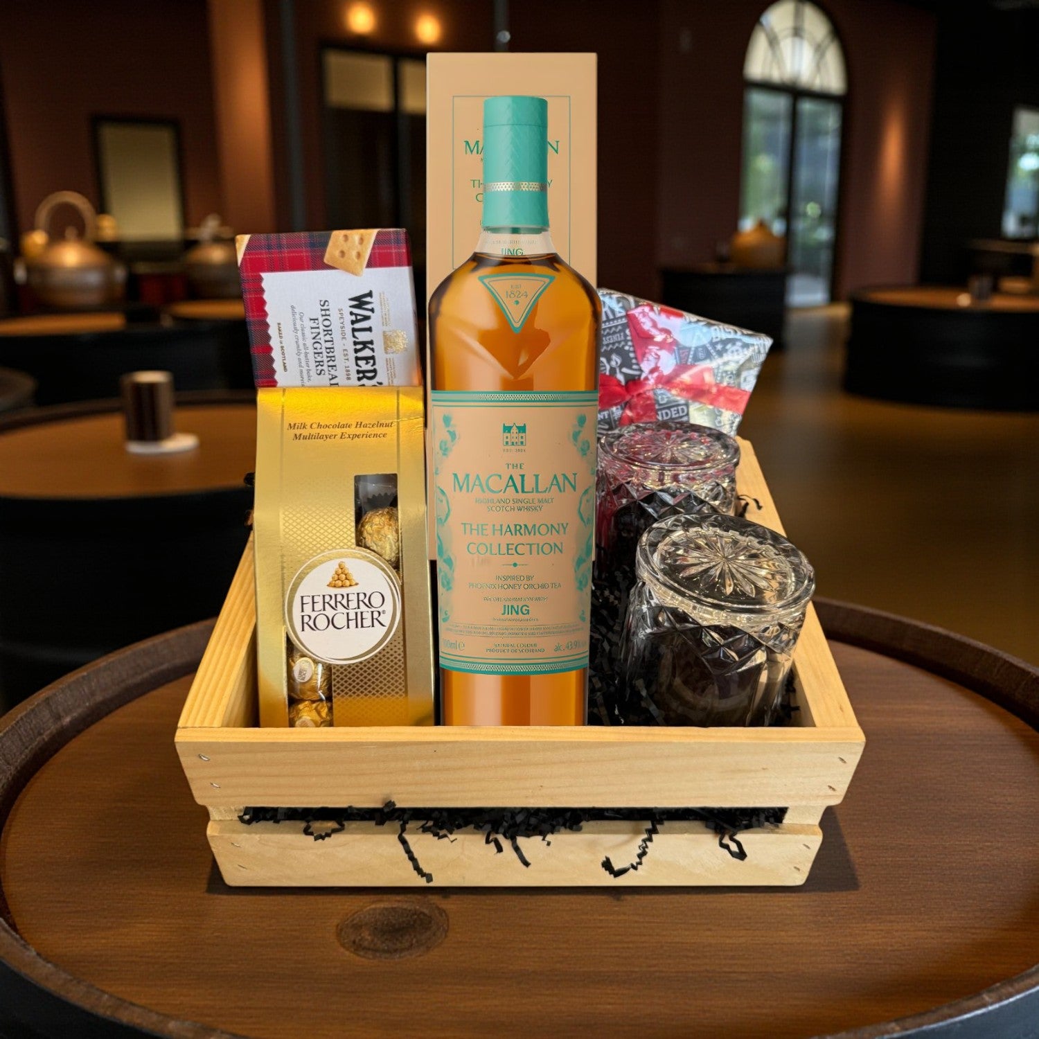 Macallan Harmony Phoenix Honey Orchid Tea Scotch Whisky Gift Crate with Ferrero Rocher, Walkers shortbread, crystal glasses, and gourmet treats displayed in a wooden crate – lifestyle scene for Total Bourbon
