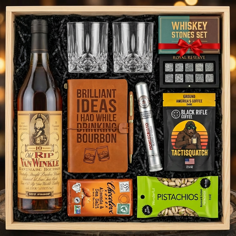 Old Rip Van Winkle 10 Year 107 Proof Top Shelf gift crate with bourbon journal, Montecristo Platinum cigar, Black Rifle Coffee, Chocolove chocolate, Wonderful Pistachios, crystal glasses, and Royal Reserve whiskey stones nestled in black zigzag crinkle paper inside wooden crate on rustic wood surface with warm ambient lighting