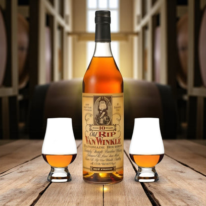 Old Rip Van Winkle 10 Year Bourbon Gift Set with two Glencairn glasses on wooden table surrounded by bourbon barrels – lifestyle shot from Total Bourbon