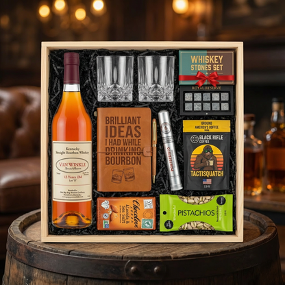 Pappy Van Winkle 12 Year Lot B Top Shelf gift crate with bourbon journal, Montecristo Platinum cigar, Black Rifle Coffee, Chocolove chocolate, Wonderful Pistachios, crystal glasses, and Royal Reserve whiskey stones nestled in black zigzag crinkle paper inside wooden crate on rustic aged oak surface with warm ambient bourbon bar lighting