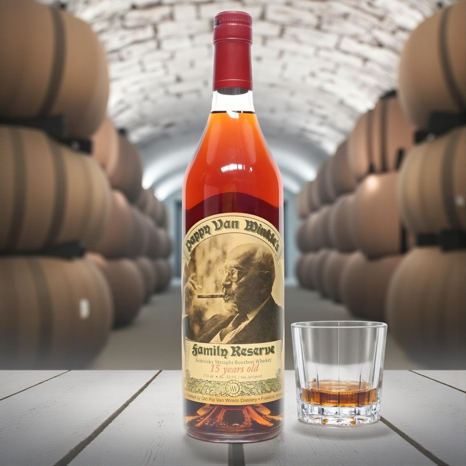 Pappy Van Winkle Family Reserve 15 Year Bourbon Santa Edition bottle on wooden table beside glass of bourbon in barrel cellar – lifestyle shot from Total Bourbon