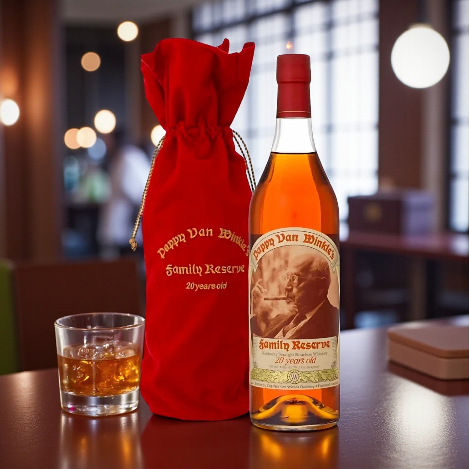 Pappy Van Winkle Family Reserve 20 Year Bourbon bottle with red velvet bag and glass of bourbon on wooden table – lifestyle shot from Total Bourbon