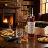 The Macallan 18 Year Old Double Cask Highland Single Malt Scotch Whisky gift crate lifestyle scene with single bottle featuring white background cap badge, two crystal-cut whiskey glasses with neat pour, Original Whiskey Stones, Ferrero Rocher chocolates, Walker's Shortbread Fingers, and open wooden crate on dark walnut table in upscale Scottish manor setting with warm ambient lighting.