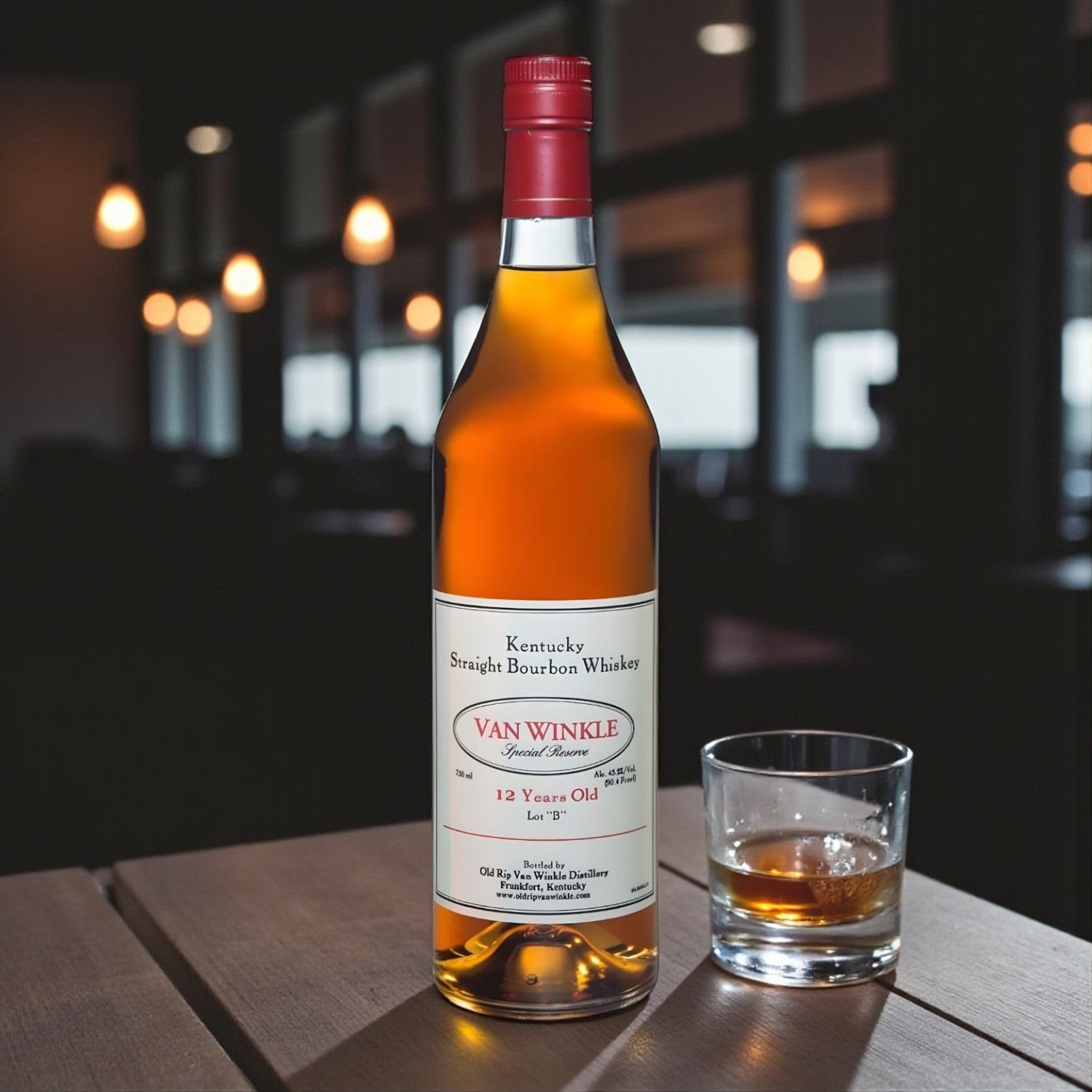 Pappy Van Winkle Special Reserve 12 Year Lot B Bourbon bottle on wooden table beside glass of bourbon with warm evening bar lighting – lifestyle shot from Total Bourbon